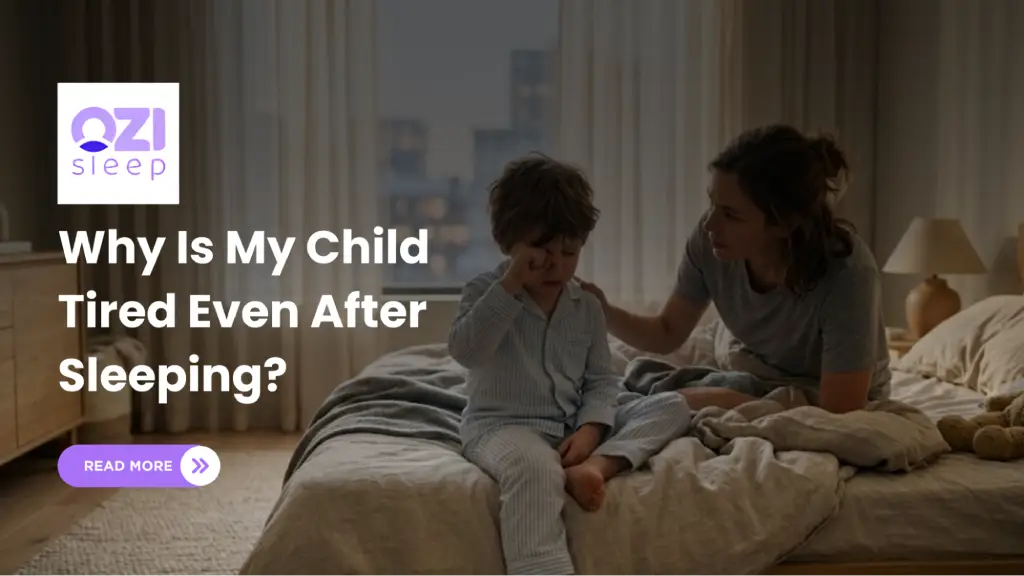 Child sitting tired on bed while parent comforts them, with text “Why Is My Child Tired Even After Sleeping?” and the Ozi Sleep logo.