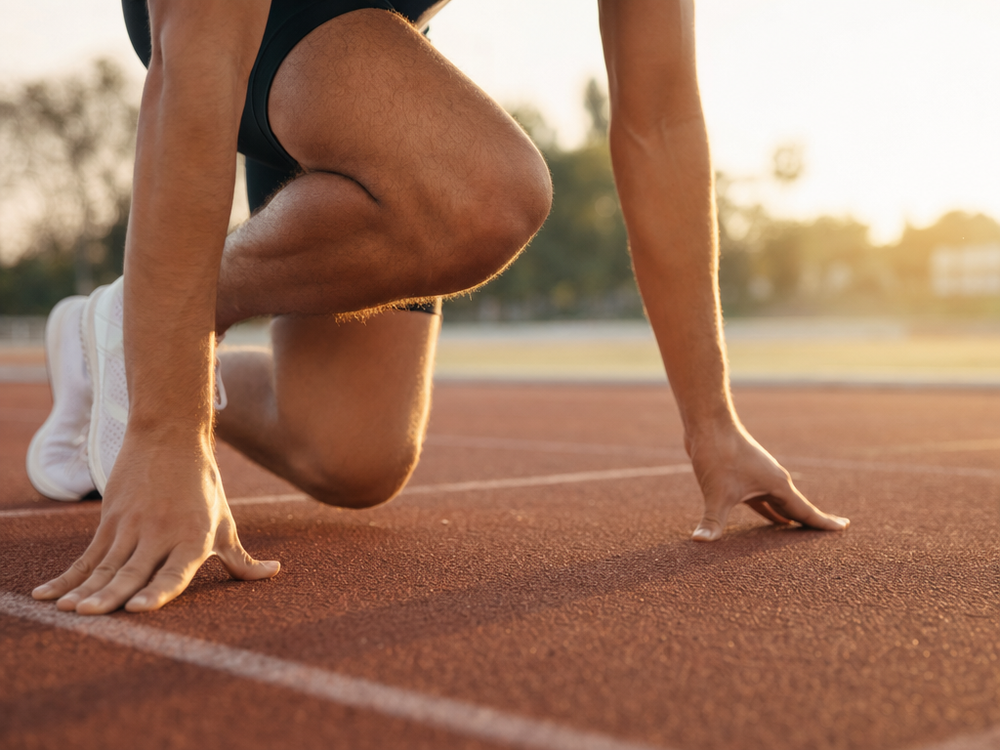 Runner at an outdoor track starting line in golden hour light