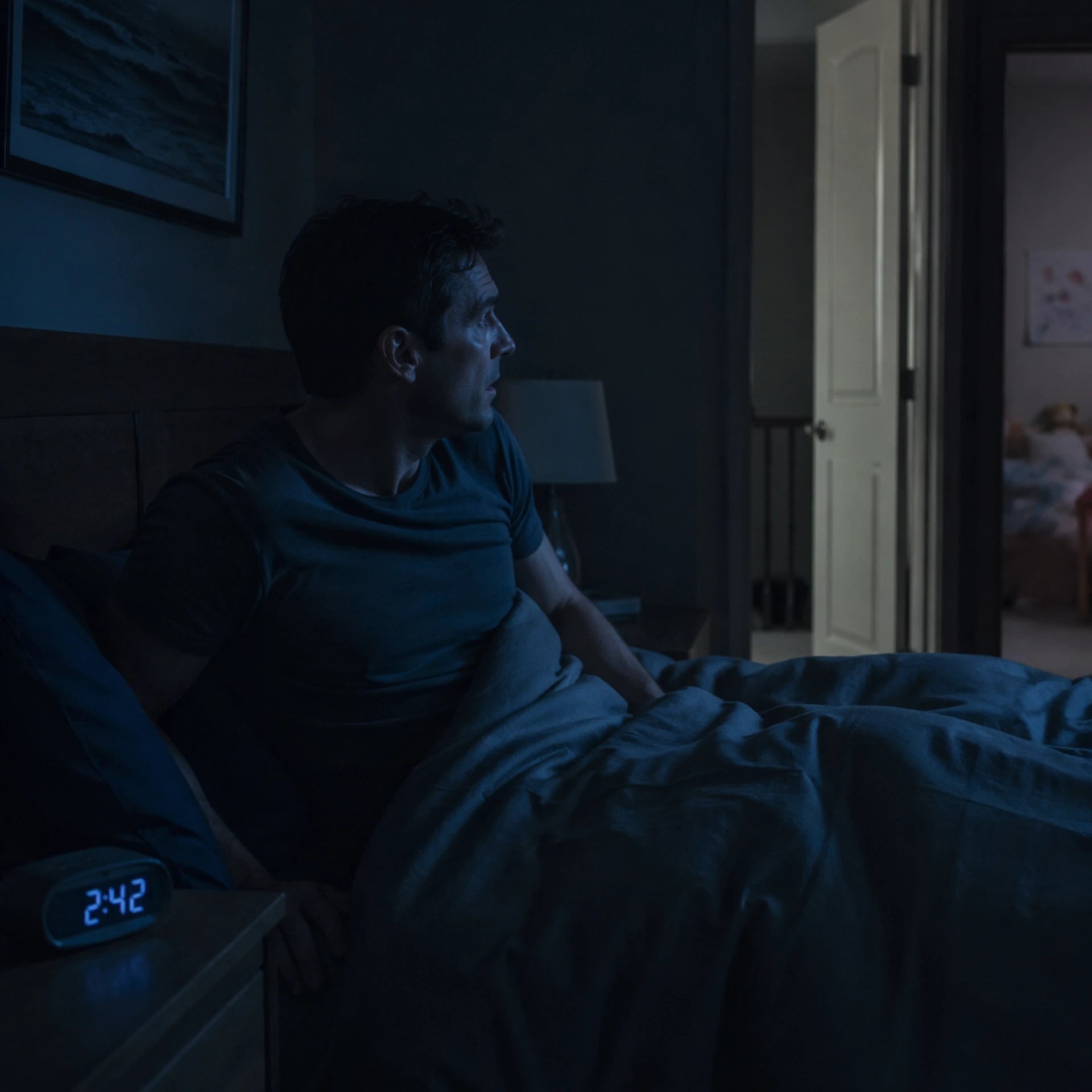 Worried parent waking at 2:42 AM staring across the hall — the sleepless nights OZI Sleep helps end with passive bed-exit alerts