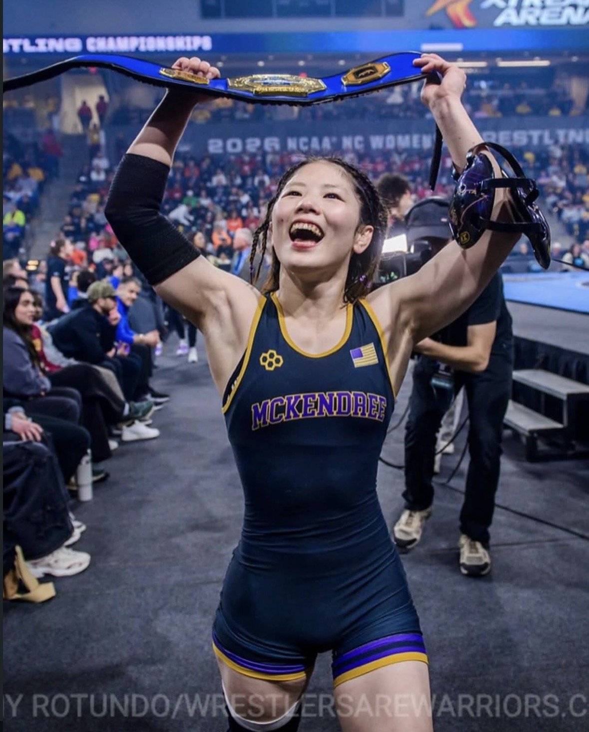 Yu Sakamoto celebrating with a championship belt at the 2026 NCAA women's wrestling championships